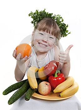 Child holds vegetables and fruit.