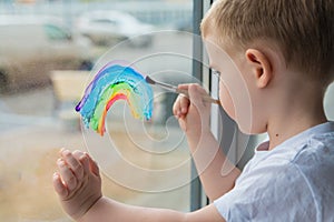 Child at home draws a rainbow on the window photo