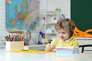 Child home studying and home education. Kid gets ready for school. Back to school. Happy smiling pupil drawing at the