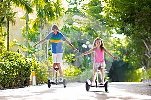 Child on hover board. Kids riding scooter photo