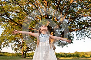 Child and a huge tree in the forest. old oak and a little girl