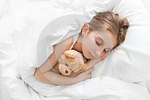 Child hugging her teddy bear in sleep