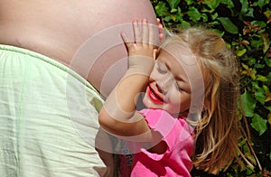 Child hugging mom pregnant belly