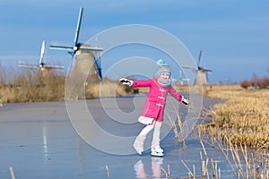 Child ice skating on frozen mill canal in Holland