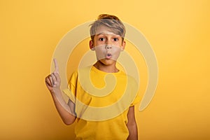 Child indicates above. Amazed and shocked expression. Yellow background