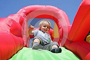 Child on inflatable bouncy castle slide