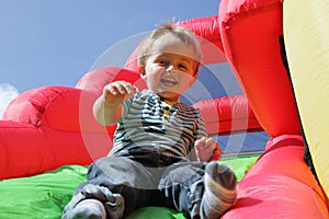 Child on inflatable bouncy castle slide