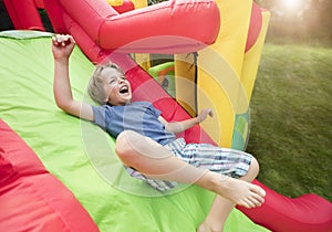 Child on inflatable bouncy castle slide