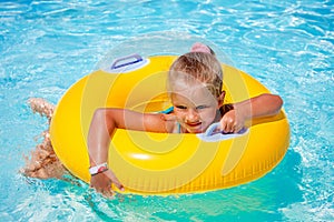 Child on inflatable ring in swimming pool