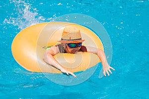 Child with inflatable ring in swimming pool. Kid boy swim in outdoor pool of tropical resort. Hot Summer. Water toys and