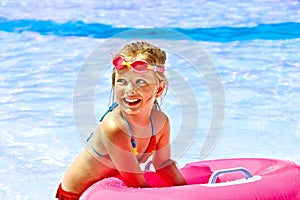 Child on inflatable in swimming pool.