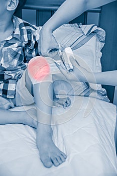Child injured. Mother bandaging son`s knee.