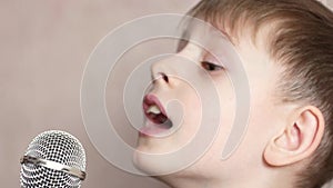 Child inspirational sings into microphone close-up. Caucasian preschooler boy having fun in his spare time sings a song in karaoke