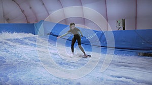 Child and instructor at Flow Rider indoor surfing training session. Teenager on water board training on simulator wave