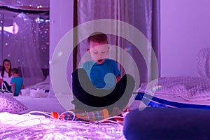 Child with intellectual disability in sensory stimulating room, snoezelen. Autistic child interacting during therapy session.