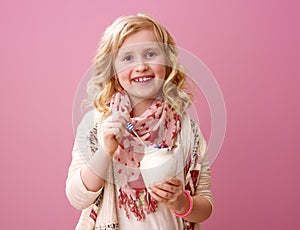 Child isolated on pink background eating farm organic yogurt