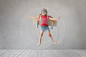 Child with jetpack jumping against grey concrete background