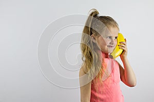 The child jokingly speaks on the banana phone and laughs