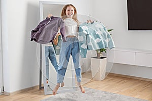 Child Jumping While Choosing Sweaters in Her Room. Morning preparation before school. Having fun