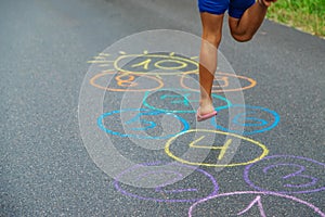 Child jumping classics on the pavement. Selective focus