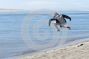 Child jumping off of sand dune