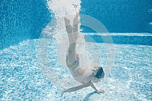 Child jumps to swimming pool and swims underwater, little active girl dives and has fun under water, healthy kids fitness