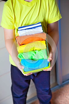 The child keeps his things. The boy puts the T-shirts in a drawer.
