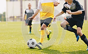Child kicking soccer ball in a duel. Running footballers compete for the ball