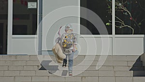 child kid boy in cap, backpack USA flag and teddy bear walking building stairs