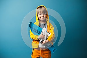 Child kid boy in yellow sweatshirt with skis in his hands. Children leisure and sports concept