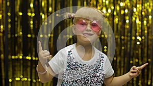 Child kid dancing, celebrating victory, fooling around. Girl posing on background with foil curtain