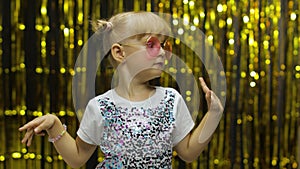 Child kid dancing, celebrating victory, fooling around. Girl posing on background with foil curtain