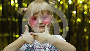 Child kid dancing, waving hands, fooling around. Girl posing on background with foil curtain