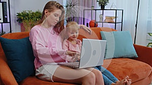 Child kid daughter having fun with mother or nanny enjoying using laptop pc watch cartoons at home