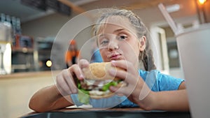 child kid eating a burger in a cafe. fast food nutrition health concept. daughter girl eats with pleasure hamburger. a