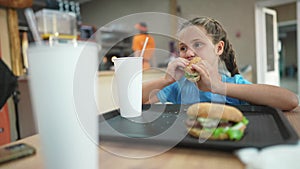 Child kid eating a burger in a cafÃ©. Fast food nutrition health concept tasty. Daughter girl eats with pleasure