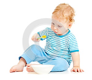 Child or kid eating from plate with spoon