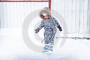 Child kid enjoy learning ice skating on skating rink overcome difficulties in a snowing park during winter holidays