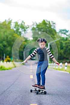 Child or kid girl playing surfskate or skateboard in skating rink or sports park at parking