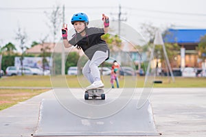 Child or kid girl playing surfskate or skateboard in skating rink or sports park at parking to wearing safety helmet elbow pads