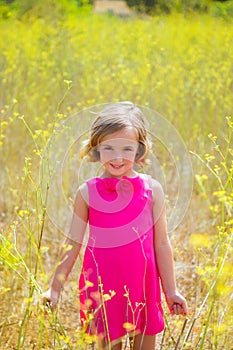 Child kid girl in spring yellow flowers field and pink dress