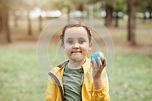 Child kid girl in a yellow raincoat holding globe in a hands outdoor in park or forest. World Earth Day concept. Green Energy,