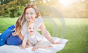 Child (kid) and mom (woman) enjoying summer day at the park. Caucasians baby (boy) with mother.