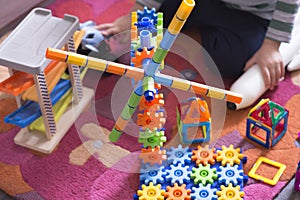 Child or kid playing in his room with educational toys on a carpet