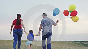 child kid runs with mother father with beautiful colorful balloons. happy family concept. group people running across