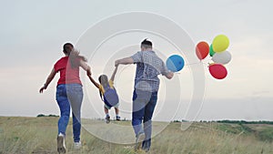 child kid runs with mother father with beautiful colorful balloons. happy family concept. group people running across