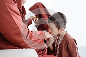 Child kissing his father`s hand to apologize