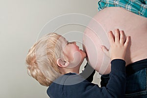 Child kissing mothers pregnancy bump