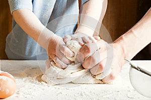 The child on the kitchen kneads the dough