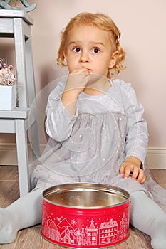 Child in the kitchen sitting and eating cookies in the shape of a rectangle